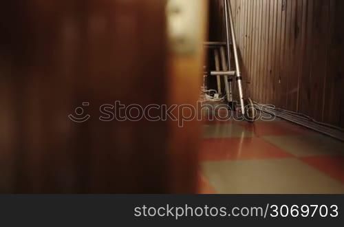 Panning shot of elderly woman moving slowly in the corridor at home with the aid of walker