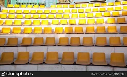Panning shot of rows of empty yellow seats in the amphitheater
