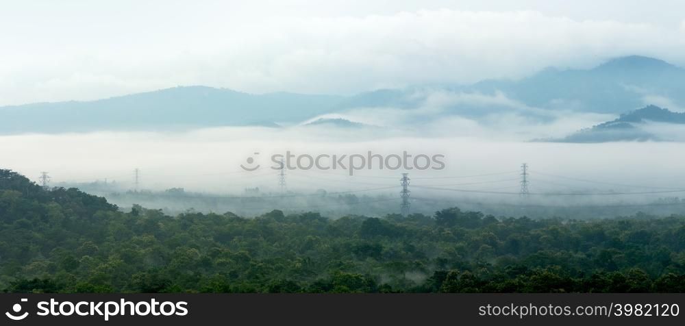 Panorama aerial view transmission tower in green forest and beautiful morning smooth fog. Energy and environment concept. High voltage power poles. Mae Moh, Lampang.. High voltage power poles in green forest. in green forest.