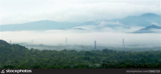 Panorama aerial view transmission tower in green forest and beautiful morning smooth fog. Energy and environment concept. High voltage power poles. Mae Moh, Lampang.. High voltage power poles in green forest. in green forest.