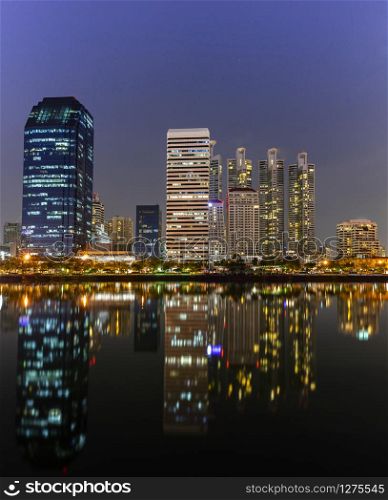 Panorama building city in business area night scene with river reflection in Bangkok, Thailand.