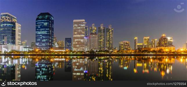 Panorama building city in business area night scene with river reflection in Bangkok, Thailand.