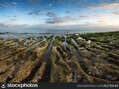 Panorama landscape looking out to sea with rocky coastline and beautful sunset sky