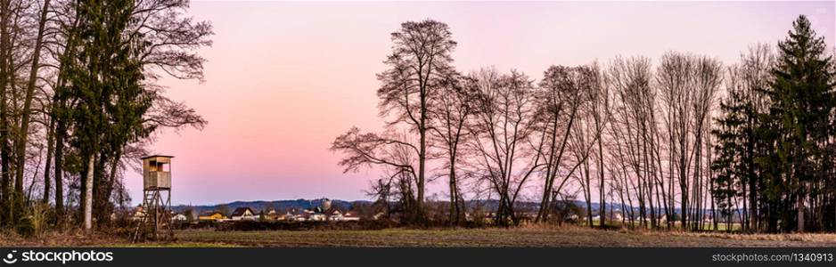 Panorama landscape with hunting tower after sunset in rural scenery against pink sky. Deer stand near Zettling Graz in Austria. Hunting concept. Panorama landscape with hunting tower after sunset in rural scenery against pink sky. Deer stand near Zettling Graz in Austria.
