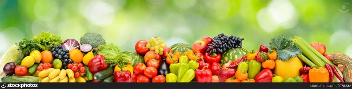 Panorama multicolored fresh fruits and vegetables on green natural background.