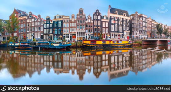 Panorama of Amsterdam canal Singel with typical dutch houses and houseboats during morning blue hour, Holland, Netherlands.