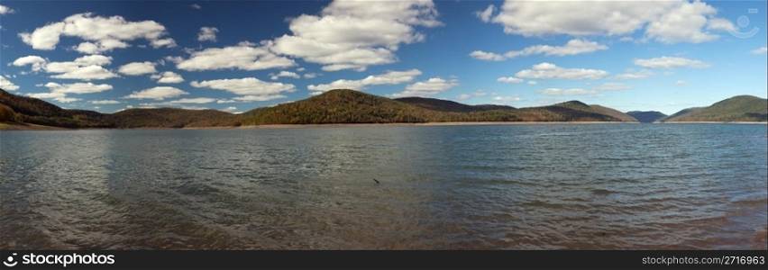Panorama of autumn scene at Cannonsville Reservoir in New York as leaves are reflected in calm river