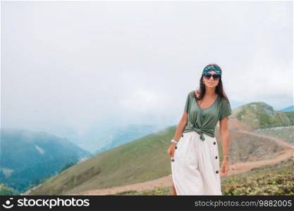 Panorama of beautiful happy young woman in mountains in the background of beautful landscape. Beautiful happy young woman in mountains in the background of fog