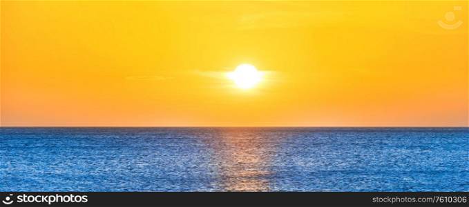 Panorama of beautiful sunset sea landscape with blue sea water and sun on yellow clear sky