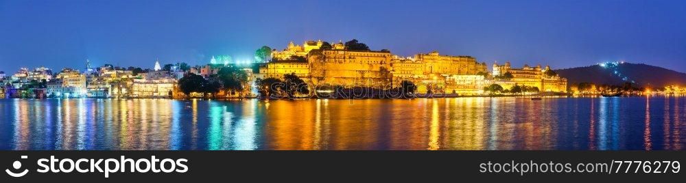 Panorama of famous romantic luxury Rajasthan indian tourist landmark - Udaipur City Palace in the evening twilight with dramatic sky - panoramic view. Udaipur, Rajasthan, India. Udaipur City Palace in the evening panorama. Udaipur, India