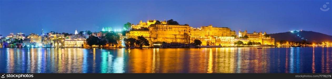 Panorama of famous romantic luxury Rajasthan indian tourist landmark - Udaipur City Palace in the evening twilight with dramatic sky - panoramic view. Udaipur, Rajasthan, India. Udaipur City Palace in the evening panorama. Udaipur, India