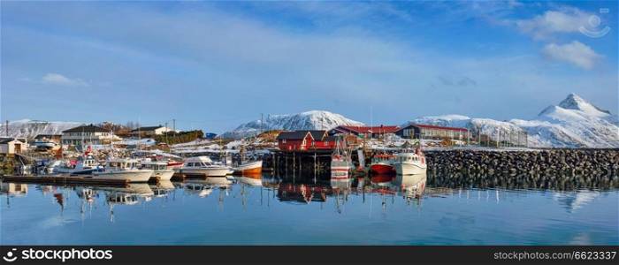 Panorama of fishing boats and yachts on pier in Norwegian fjord in village on Lofoten islands in winter, Norway. Fishing boats and yachts on pier in Norway
