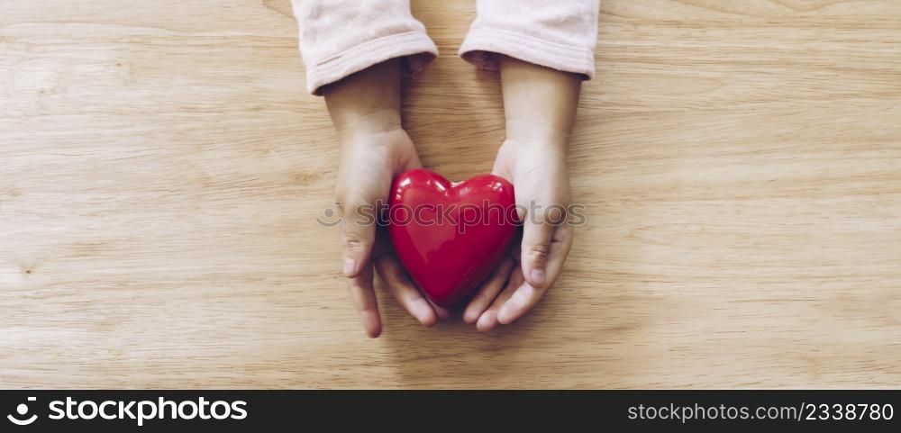 panorama of girl hand holding heart on wood table background