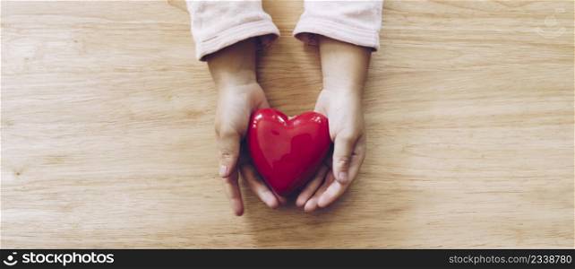 panorama of girl hand holding heart on wood table background