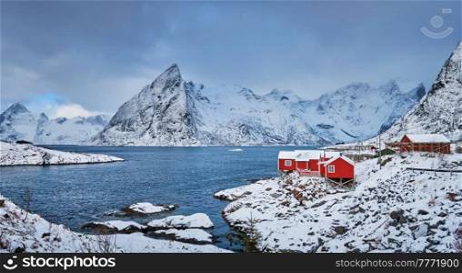 Panorama of Iconic Hamnoy fishing village on Lofoten Islands, Norway with red rorbu houses. With falling snow in winter.. Hamnoy fishing village on Lofoten Islands, Norway