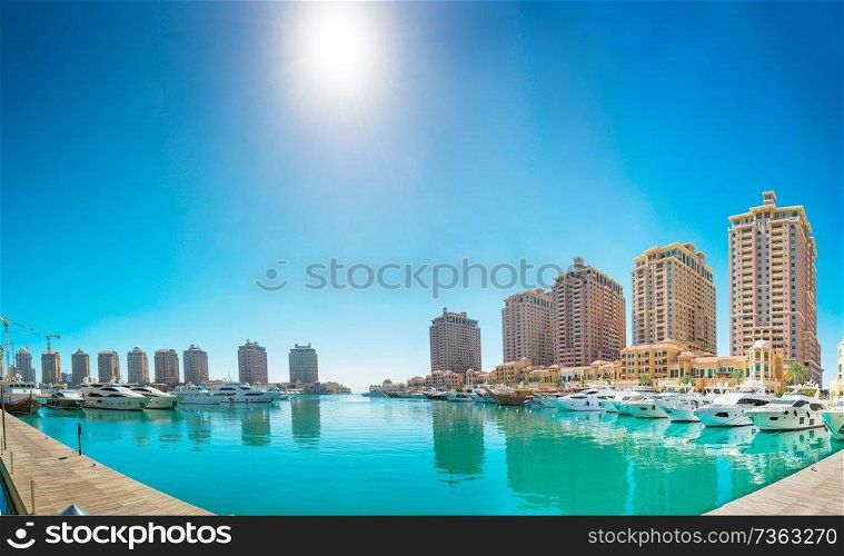 Panorama of luxury residential buildings of Pearl Qatar and white yachts at Porto Arabia marina. Doha, Qatar