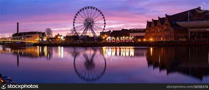 Panorama of Motlawa River and Ferris wheel with water reflection in Old Town of Gdansk at night, Poland. Old Town and Motlawa River in Gdansk, Poland