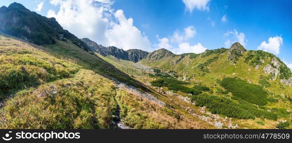 Panorama of mountain range with green hills, clouds and sky