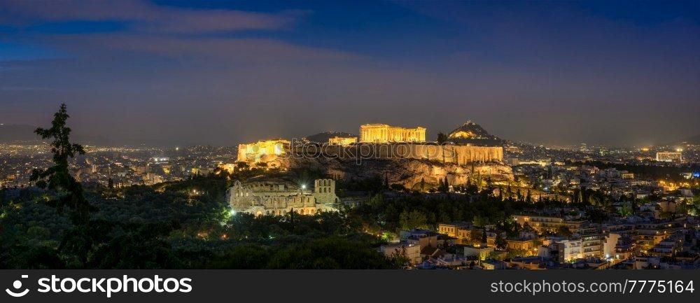 Panorama of Parthenon Temple and Amphiteater are iconic greek tourist landmark at Acropolis of Athens and ancient European civilization architecture. View from Philopappos Hill at night. Greece. Parthenon Temple and Amphiteater are ancient architecture at the Acropolis, Athens, Greece