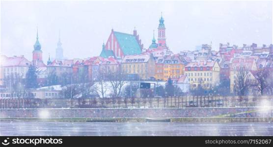 Panorama of Royal Castle and colorful houses by the Vistula River in the snowy evening, Warsaw, Poland.. Old Town and river Vistula at night in Warsaw, Poland.