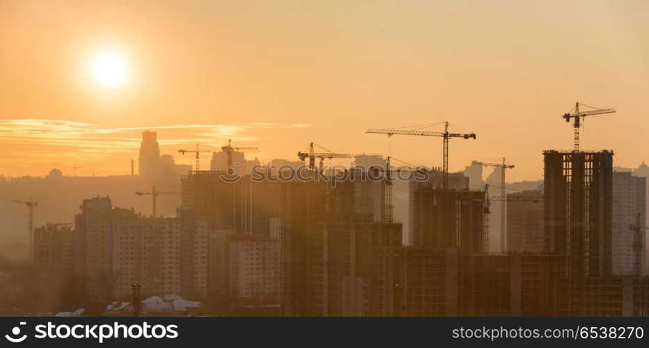 Panorama of sunset in the city. Panorama of sunset in the city with silhouette of buildings and industrial cranes