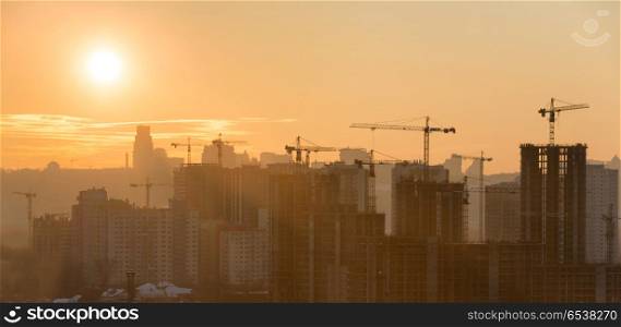 Panorama of sunset in the city. Panorama of sunset in the city with silhouette of buildings and industrial cranes