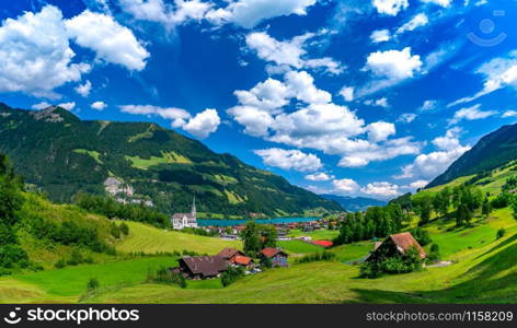 Panorama of swiss village Lungern with church and traditional wood houses on lake Lungernsee in sunny summer day, Obwalden, Switzerland. Swiss village Lungern, Switzerland