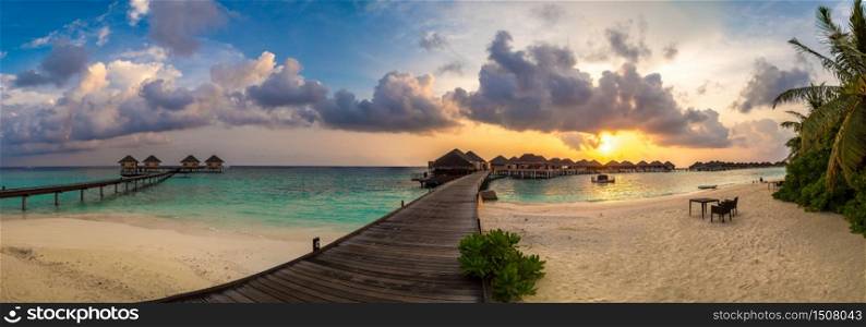 Panorama of Tropical sunset over bungalows at Tropical beach in the Maldives at summer evening