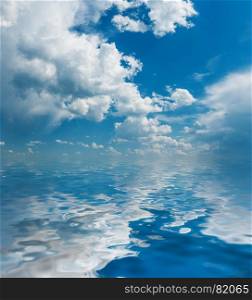 Panorama of vast blue summer sky with fluffy white cumulus clouds reflected in a water surface with small waves