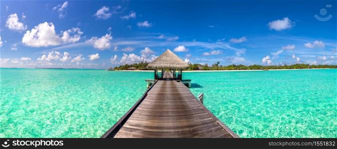 Panorama of Water Villas (Bungalows) and wooden bridge at Tropical beach in the Maldives at summer day