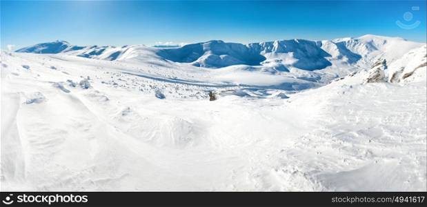 Panorama of white winter mountains with snow and bright shining sun and sunrays