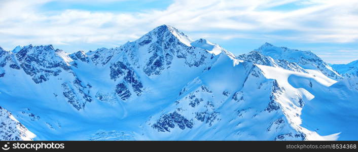 Panorama of winter mountains in snow. Mountains in snow. Panorama of winter landscape with peaks and blue sky