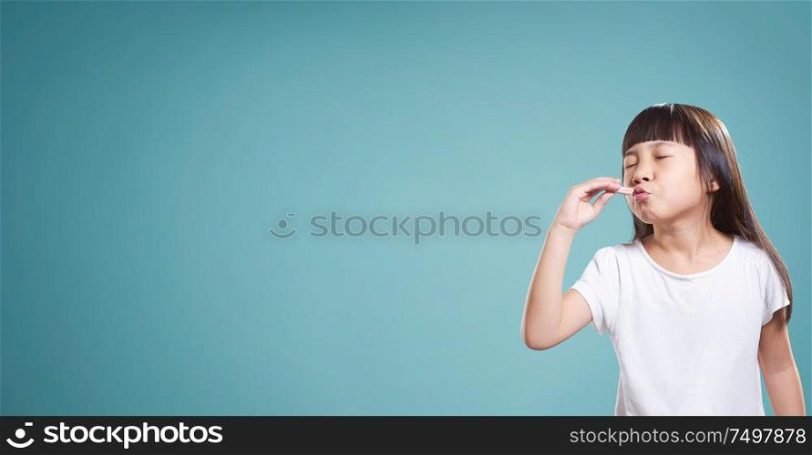 Panorama portrait of asian little happy girl with good taste chocolate . isolated on light blue background .