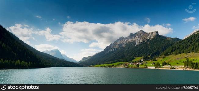 panorama view of an idyllic and picturesque turquoise mountain lake surrounded by green forest and mountain peaks in the Swiss Alps near Sufers