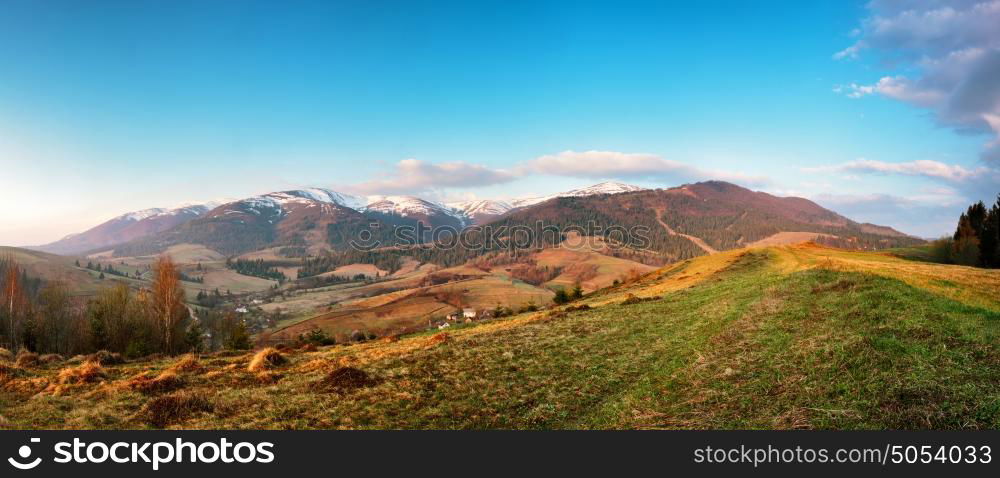 Panorama view of snow capped mountain peaks in spring time. Mountains in morning light.Idyllic Spring alpine morning landscape with fresh green meadows and snow-capped mountain tops in the background.
