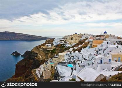 Panorama view of the island of Santorini in Greece under cloudy sky.
