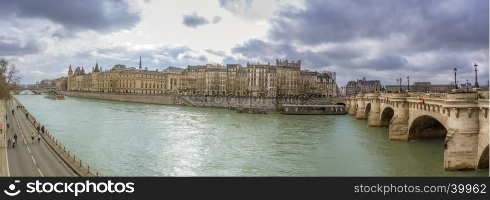 Panorama with a famous bridge of Paris called in french Pont Neuf and the river Seine under a cloudy February sky.