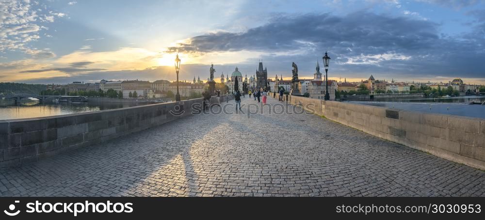 Panorama with Charles Bridge at sunrise. Panoramic view with the famous Charles Bridge, the Vltava river and the Prague city, with the golden light of the sunrise over them.