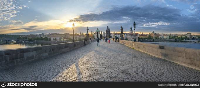 Panorama with Charles Bridge at sunrise. Panoramic view with the famous Charles Bridge, the Vltava river and the Prague city, with the golden light of the sunrise over them.