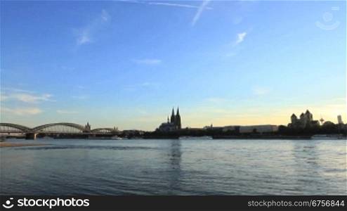 Panoramablick auf das ruhige Wasser des Rheins, dahinter liegt die Stadt K?ln im Schattenlicht