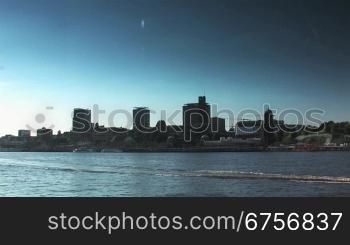 Panoramablick auf den Hamburger Hafen, das Wasser und der Skyline von links nach rechts. Ein Motorboot fShrt auf der Elbe und zieht Wellen hinter sich.