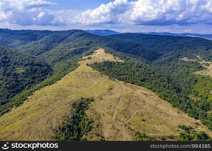 Panoramic Drone Aerial View view of mountain peaks. Hilltops covered with forest. Green nature background aerial view mountain landscape.