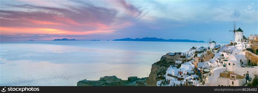 Panoramic famous view, Old Town of Oia or Ia on the island Santorini, white houses and windmills at sunset, Greece