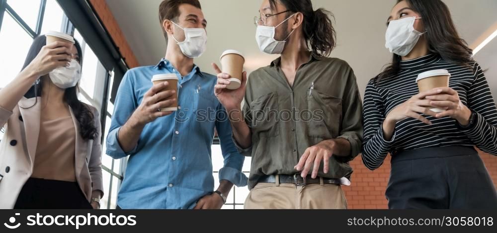 Panoramic group of business worker team with takeout coffee cup walking back to office after lunch break. They wear protective face mask in new normal office preventing coronavirus COVID-19 spreading.