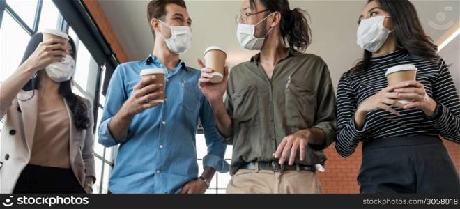 Panoramic group of business worker team with takeout coffee cup walking back to office after lunch break. They wear protective face mask in new normal office preventing coronavirus COVID-19 spreading.