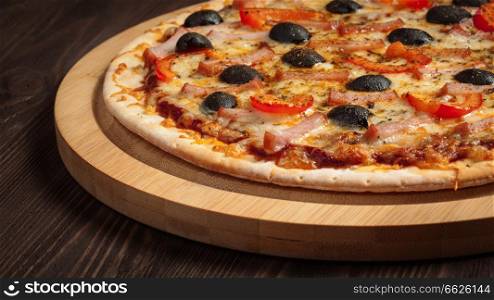 Panoramic image of ham pizza with capsicum and olives on wooden board on table close up. Ham pizza close up