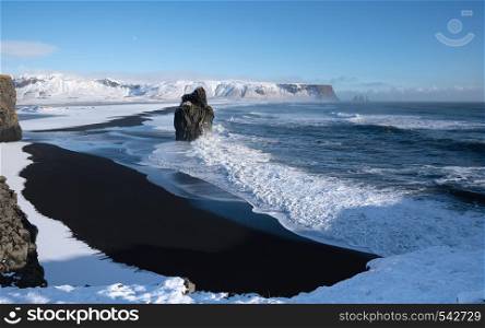 Panoramic image of the coastal landscape of Cape Dyrholaey on a winter day with snow-covered coastline, Iceland