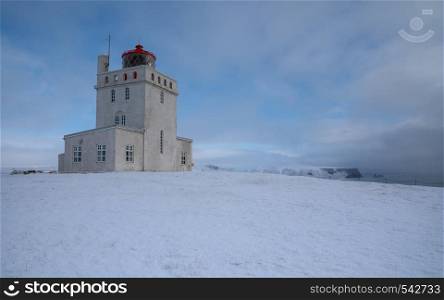 Panoramic image of the lighthouse of Cape Dyrholaey with snow and early morning light, winter in Iceland