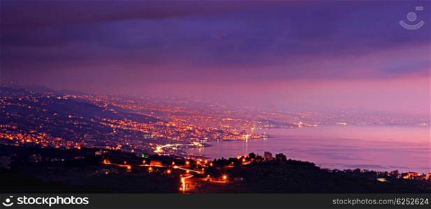Panoramic mountains city at night with purple sky &amp; sea