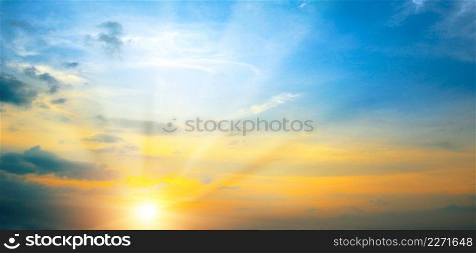 Panoramic photo bright spring sunset with blue sky, red sun and sunbeams.